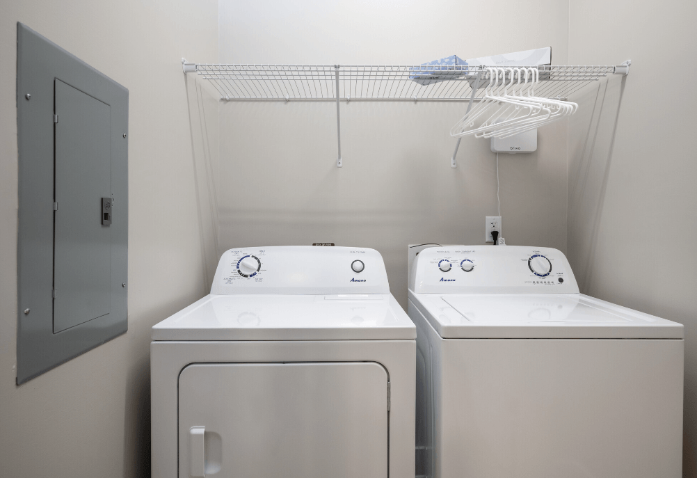 two washers and dryers in a white laundry room with a rack above them at Park View Greer, Greer, 29365