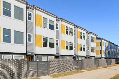 A row of modern townhouses with grey, white, and yellow exterior panels.