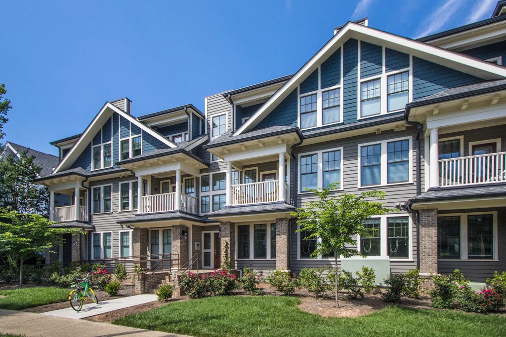 A row of houses with a bicycle parked in front of the first one.