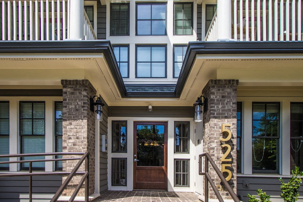 The front entrance of a building with a glass door and a stone pillar.
