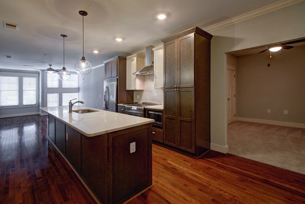 A kitchen with wooden floors and dark brown cabinets.