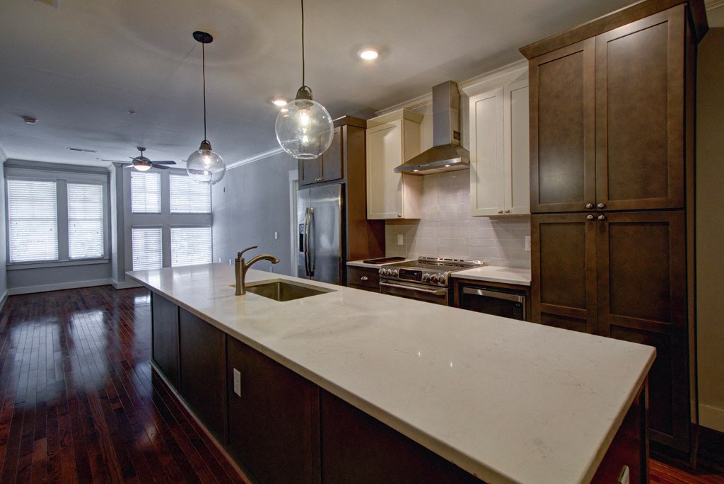 A kitchen with a white counter top and wooden cabinets.