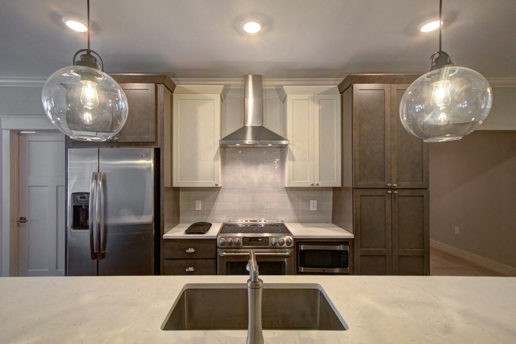 A modern kitchen with a stainless steel refrigerator and a center island with a sink.