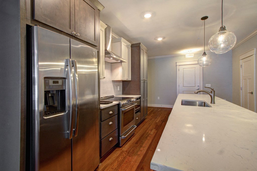 A modern kitchen with stainless steel appliances and wooden floors.