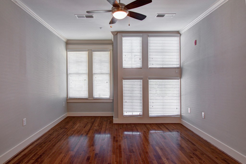 A room with a ceiling fan and wooden floors.