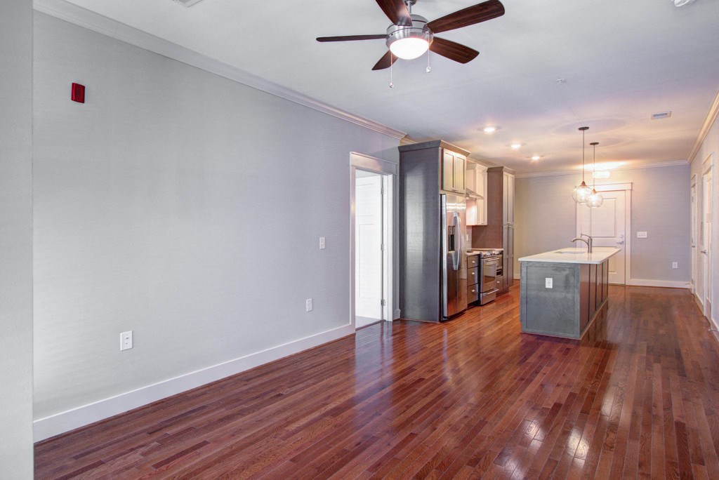A room with a ceiling fan and a refrigerator.