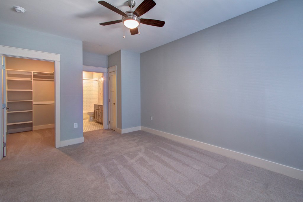 A room with a ceiling fan and carpeted floor.
