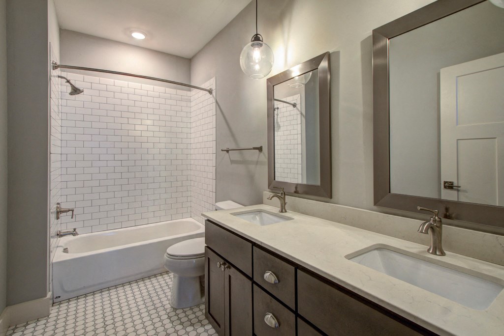 A white tiled bathroom with a white tub and sink.