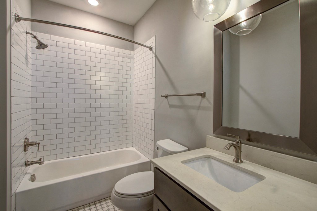 A white bathroom with a white tub, toilet, and sink.