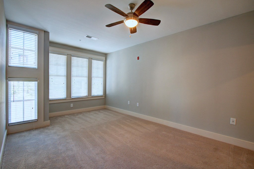 A room with a ceiling fan and carpeted floor.