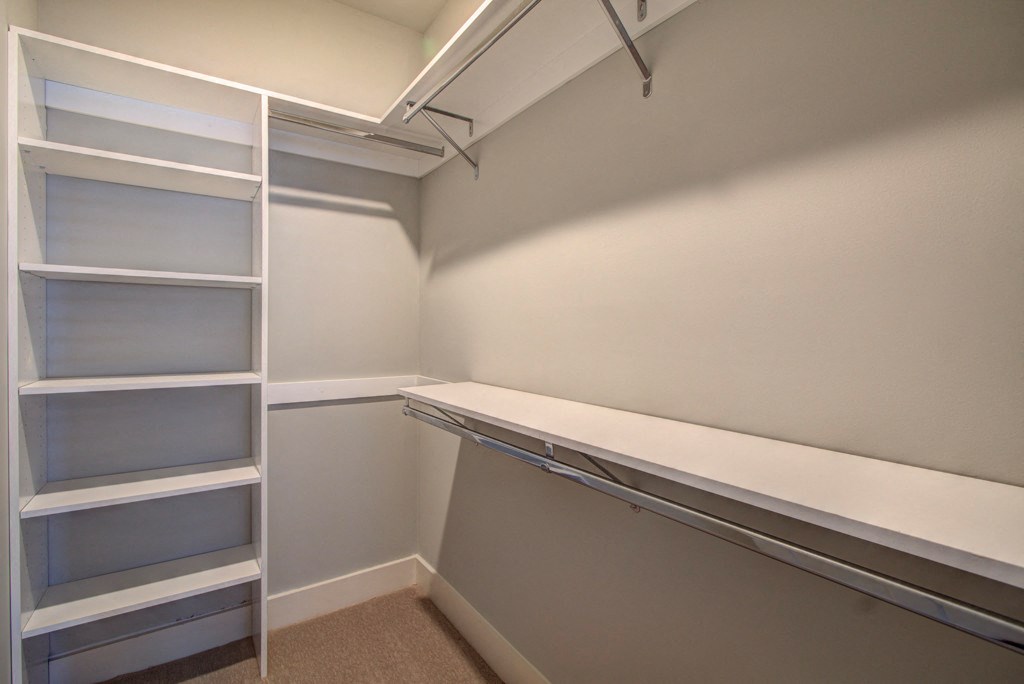 A white shelving unit with glass doors is in a room with white walls.