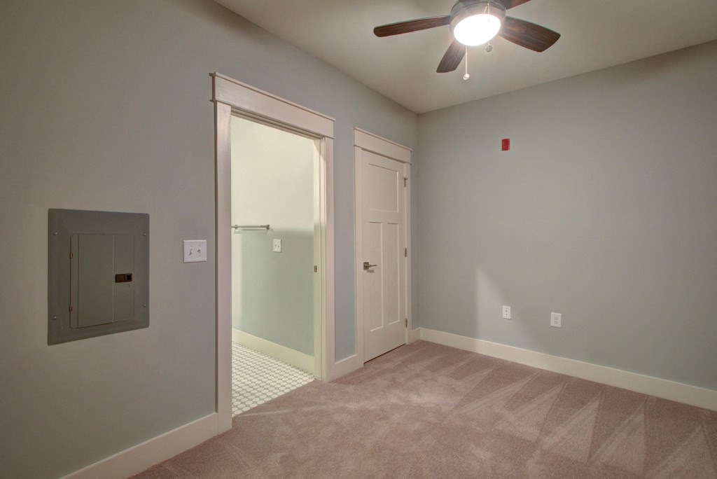 A room with a ceiling fan and a door.