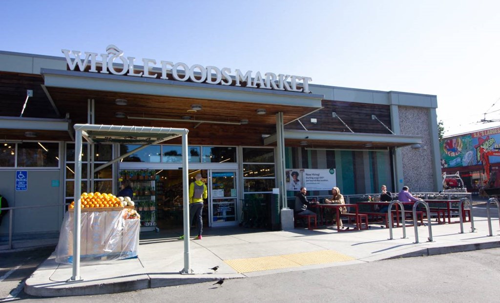 the front of a grocery store with people sitting at tables
