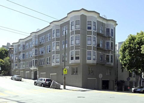A street view of a building with cars parked in front.