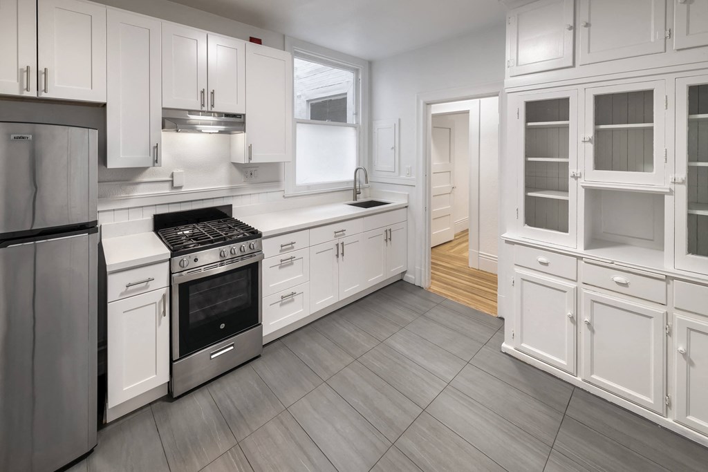 a renovated kitchen with white cabinets and stainless steel appliances