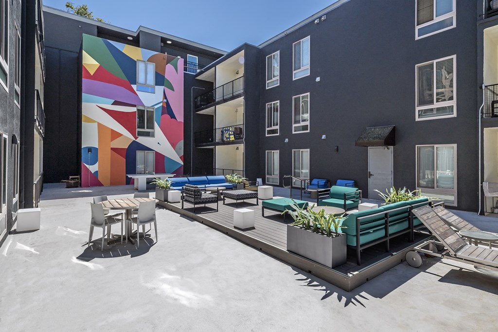 a courtyard with tables and chairs and a mural on a building