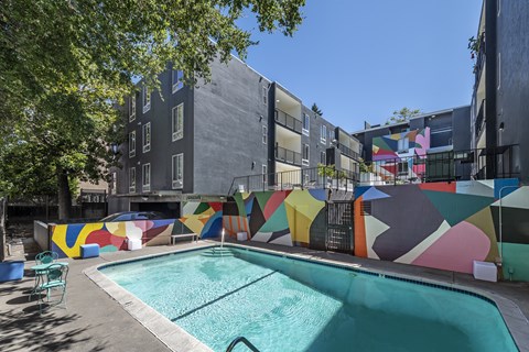 an apartment pool with a mural on the side of a building