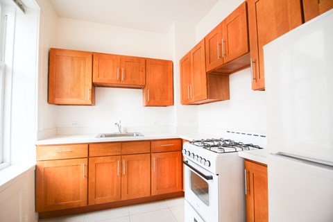 an empty kitchen with wooden cabinets and white appliances
