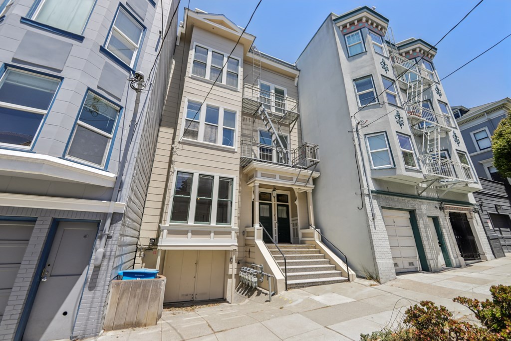 A row of three-story houses with white and grey facades and blue doors.