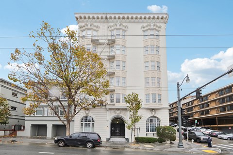 A large white building with a black car parked in front.