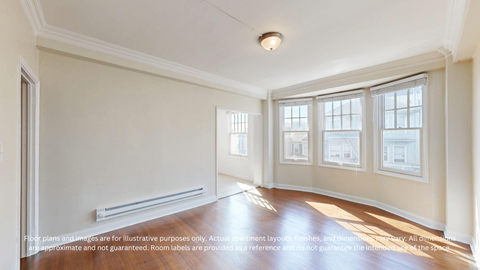A spacious room with a wooden floor and large windows.