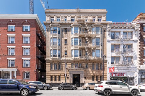 A row of buildings with cars parked in front.