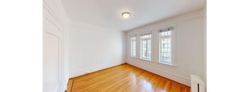 a living room with white walls and wood floors and a window