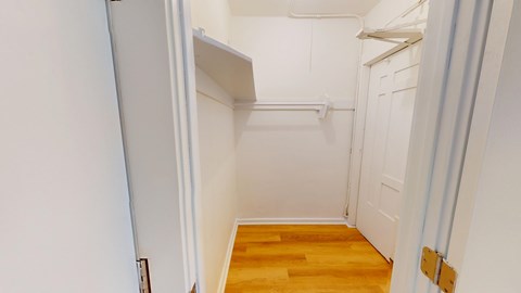 A white door is open to a small room with a wooden floor.