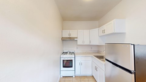 A kitchen with white cabinets and a black refrigerator.