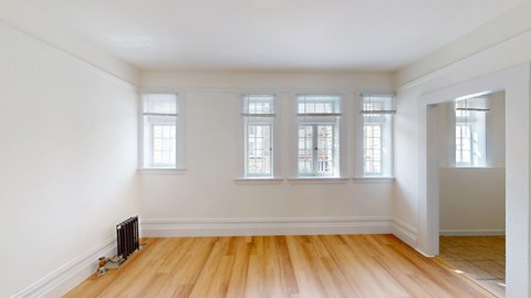 A room with wooden floors and three windows.