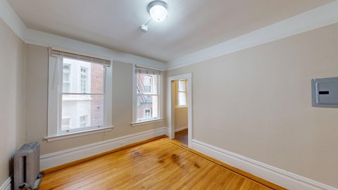A room with wooden floors and a window overlooking a building.