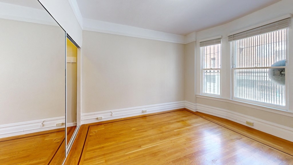 an empty room with wooden floors and a mirror in the corner