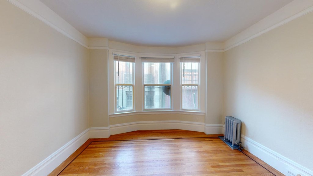 an empty room with three windows and a radiator