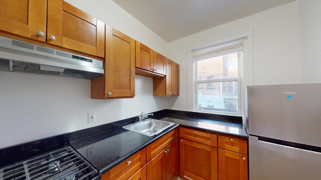 a kitchen with black countertops and wooden cabinets and a window