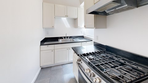 A kitchen with a black stove top oven and white cabinets.