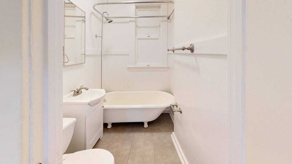 a white bathroom with a tub and a sink and a mirror