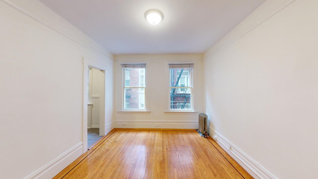 a living room with wood floors and two windows