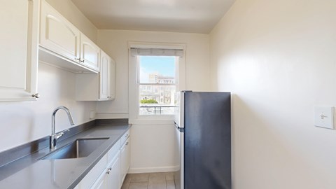 A kitchen with white cabinets and a black refrigerator.