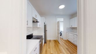 a renovated kitchen with white cabinets and wood floors