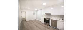 an empty kitchen with white cabinets and a stainless steel stove
