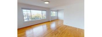 an empty living room with wood floors and large windows