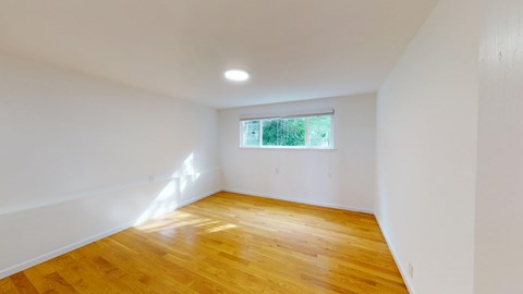 A room with wooden flooring and a window.