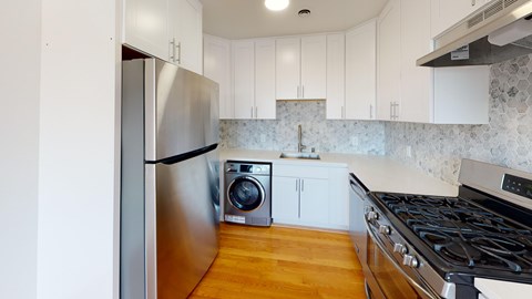 A kitchen with a stainless steel refrigerator and a black stove top.