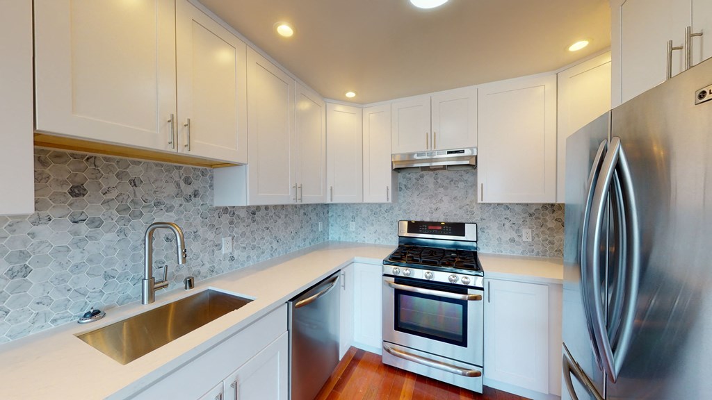 Kitchen with multiple cabinets, refrigerator, stove, and sink