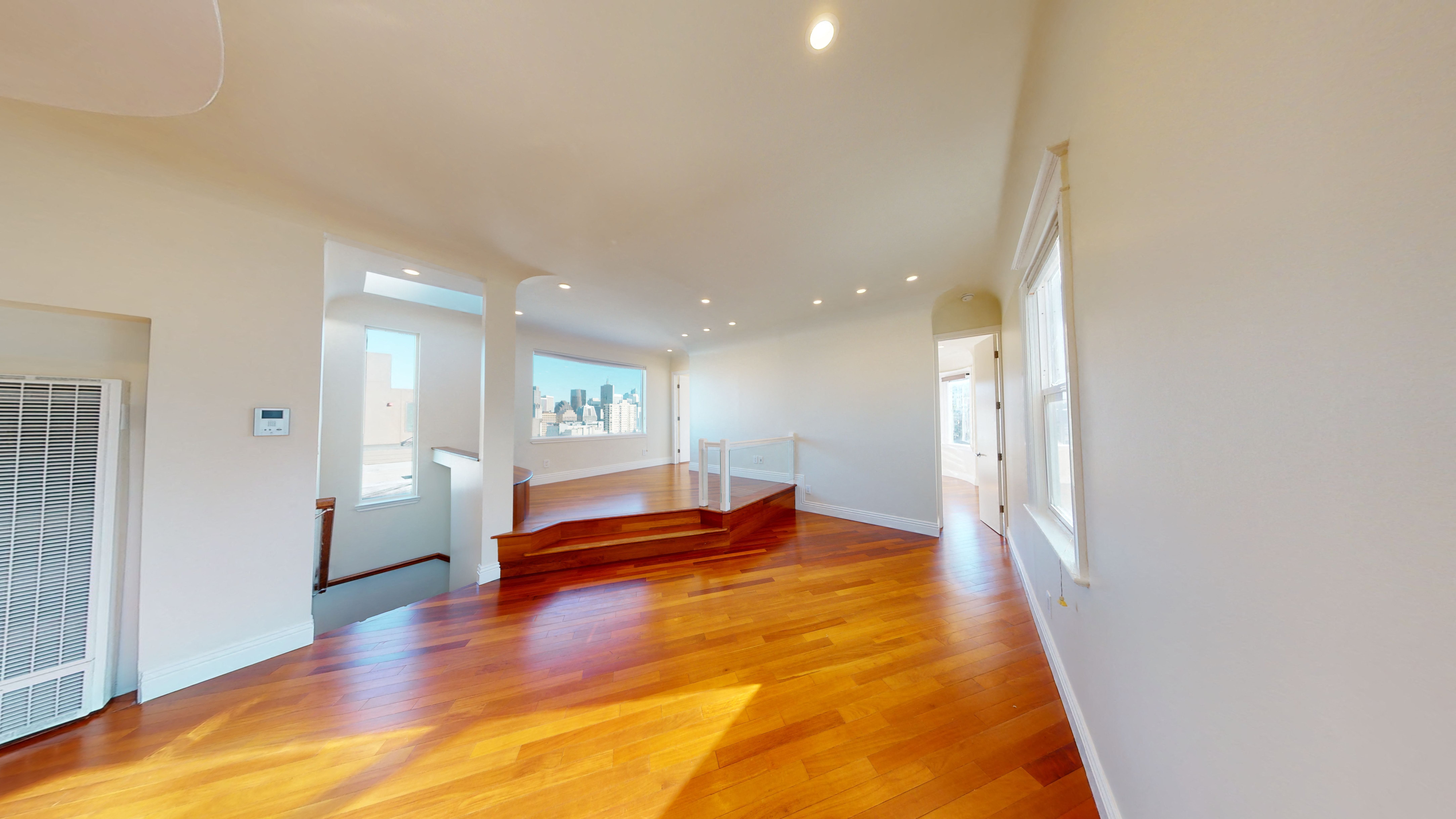 spacious living room with a hard wood floor and white walls