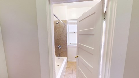 A white door is open to a bathroom with a brown towel on the wall.