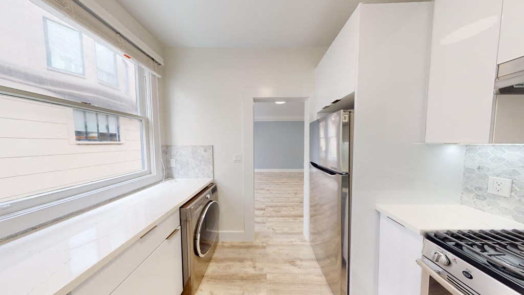 a kitchen with white cabinets and stainless steel appliances and a window