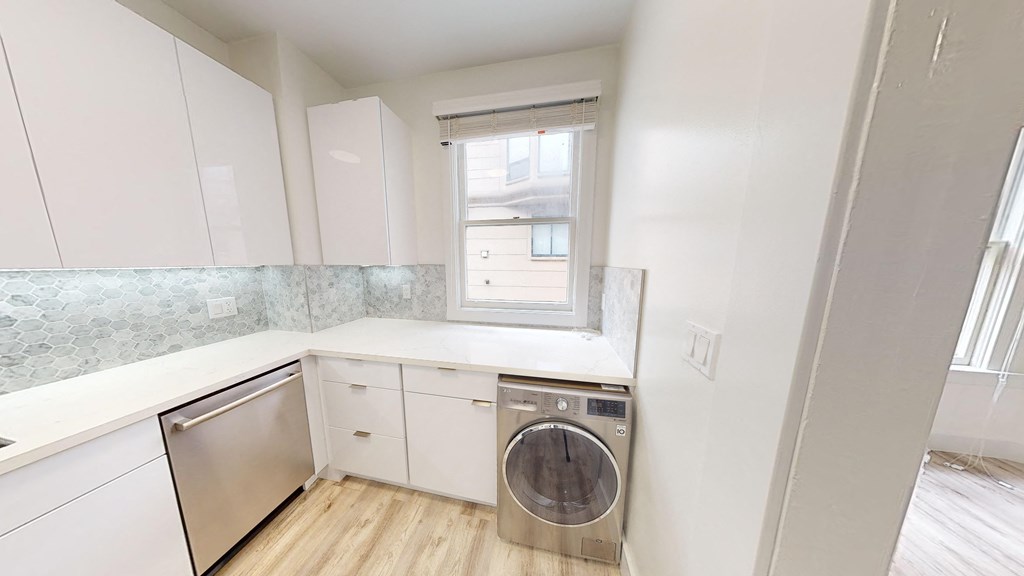 a kitchen with white cabinets and a washing machine