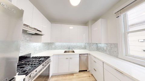 a renovated kitchen with white cabinets and stainless steel appliances