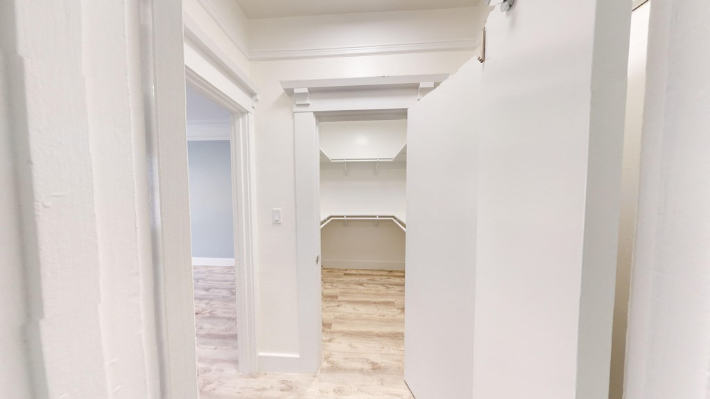 an empty room with white walls and a hallway with a door open to a bathroom
